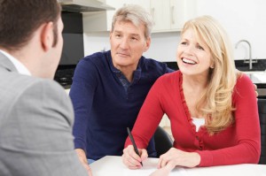 Mature Couple With Financial Advisor Signing Document At Home