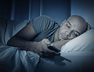 young cell phone addict man sleeping at night in bed while using